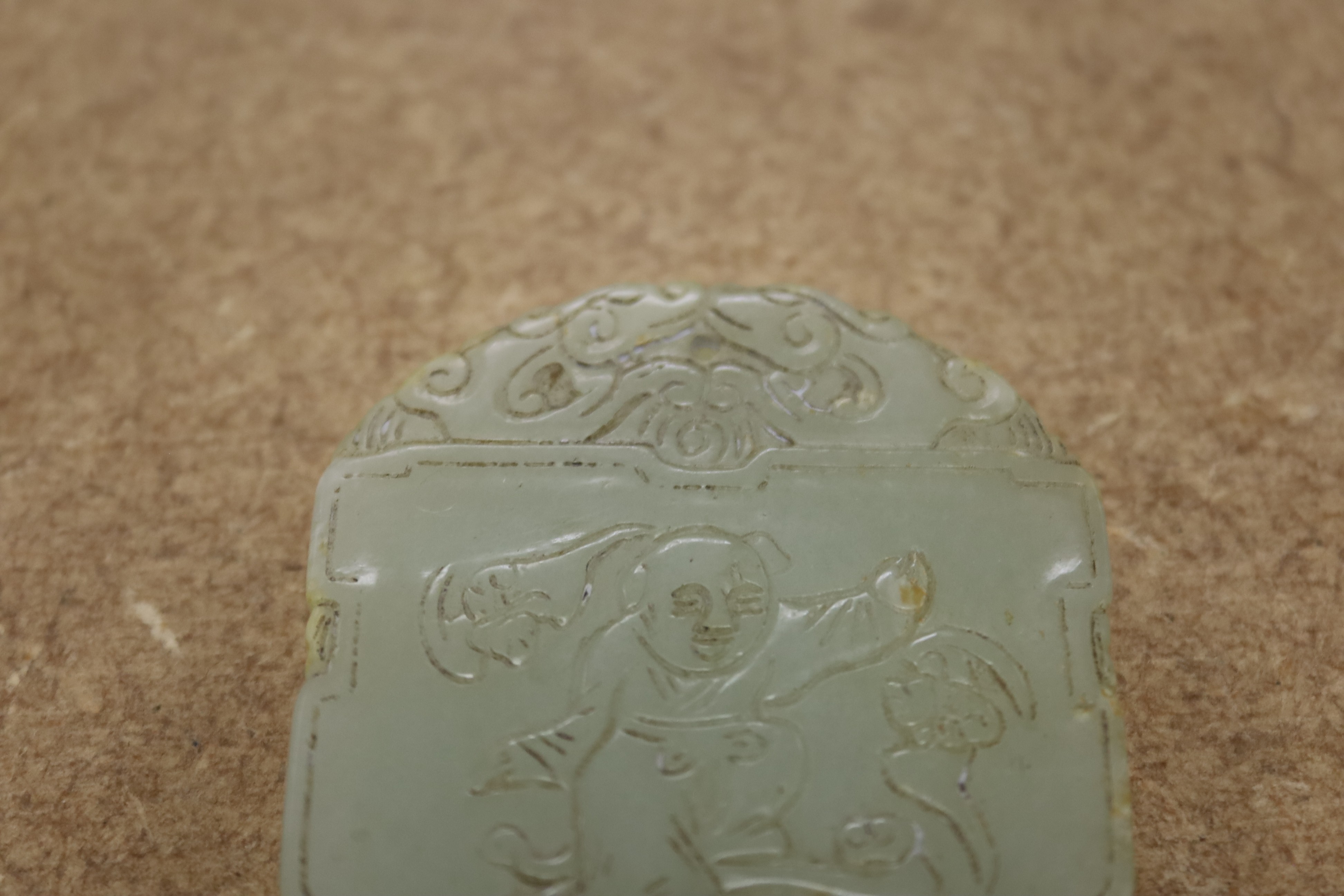A Chinese pale celadon jade plaque, boy and bats, 5cm wide